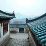 Toit bleu traditionnel en tuiles de céramique d'un village chinois avec ornements sculptés et murs blanchis à la chaux